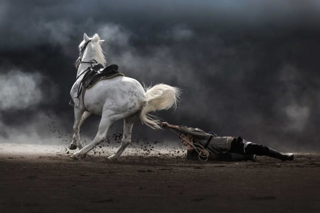 Partha Pratim Roy, India. Winner, Best Single Image in Faces, People, Cultures Portfolio
Location: Mount Bromo, Jawa Timur, East Java, Indonesia
“On the windswept sands of Mount Bromo, an Indonesian horseman struggles to control his aggressive, energetic horse. The man, gripping tightly, is thrown to the ground, volcanic dust clinging to his face lined with years of toil. Life here is unyielding, demanding strength and resilience from man and beast alike. For the Tenggerese, this is more than survival—it’s a way of life, etched in their culture. The horseman, undeterred, reflects a people whose enduring spirit thrives even amidst the challenges of this untamed terrain.”