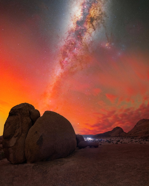 African Savanna Under the Lights of Southern Aurora” – Egor Goryachev,
Spitzkoppe, Namibia.
Everyone remembers that May night when the Northern Lights were visible across Europe and America. Unbelievably, I had the chance to witness them in Namibia, near the Tropic of Capricorn. Early in the night, the eastern sky was clear, where the Milky Way was set to rise. Seizing the opportunity, I prepared my gear for a 50mm panorama.
As I worked through the layout of the Milky Way’s core, I noticed a red spot on the horizon. Over the next few hours, it grew into a massive red explosion, illuminating much of the sky. The glow persisted throughout the night as the Milky Way shifted westward, forming a morning arch. The southern sky glowed red and orange, with the Milky Way rising through the vibrant hues.
For the first time, I realized I had captured a Southern Aurora. It was a moment of pure joy.
