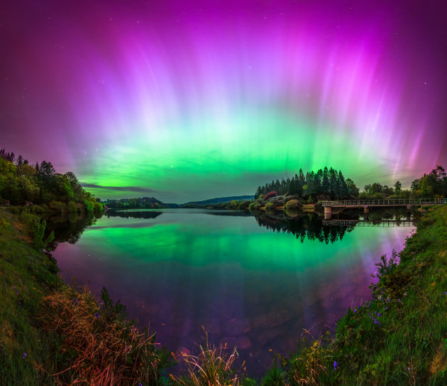 “Celestial Reflection” – Max Trafford, Dartmoor National Park, United Kingdom.
This was my second encounter with the Northern Lights, and what an unforgettable experience it was. After a long day at work and a steady stream of Aurora alerts on my phone, I left at 5 p.m., grabbed my camera gear, and headed to the darkest spot I knew. With no phone service, I wasn’t sure if the high activity would last through the night, but I remained hopeful and began capturing photos.
Almost immediately, the green glow on the horizon erupted into a stunning display of vibrant lights. I couldn’t believe my eyes!
