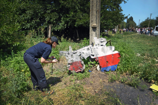 An AFP member examines a piece of the MH17 fuselage in Ukraine. The AFP, along with the investigative authorities from Belgium, Malaysia, Ukraine and the Netherlands, formed a Joint Investigative Team following the downing of Malaysian Airlines flight MH17.