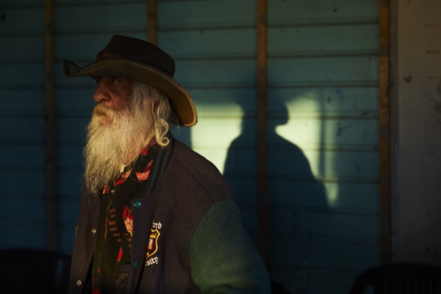 During a tour of the site, Uncle Peter Robinson #1 stands in the weather shed, a place where the boys did their chores. The setting sun is reflected on an outside window, bouncing into the weather shed and casting his shadow. Image: Tace Stevens for Magnum Foundation & World Monuments Fund.