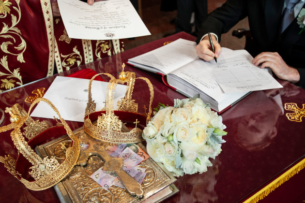 Sometimes it can be the abstract photos that help to the story, like this photo made during the signing of the register. Although we can see hands of both the grooms man and the priest in the picture, it is the two crowns, the cash, the cross and the bouquet that also help remind us of the day.